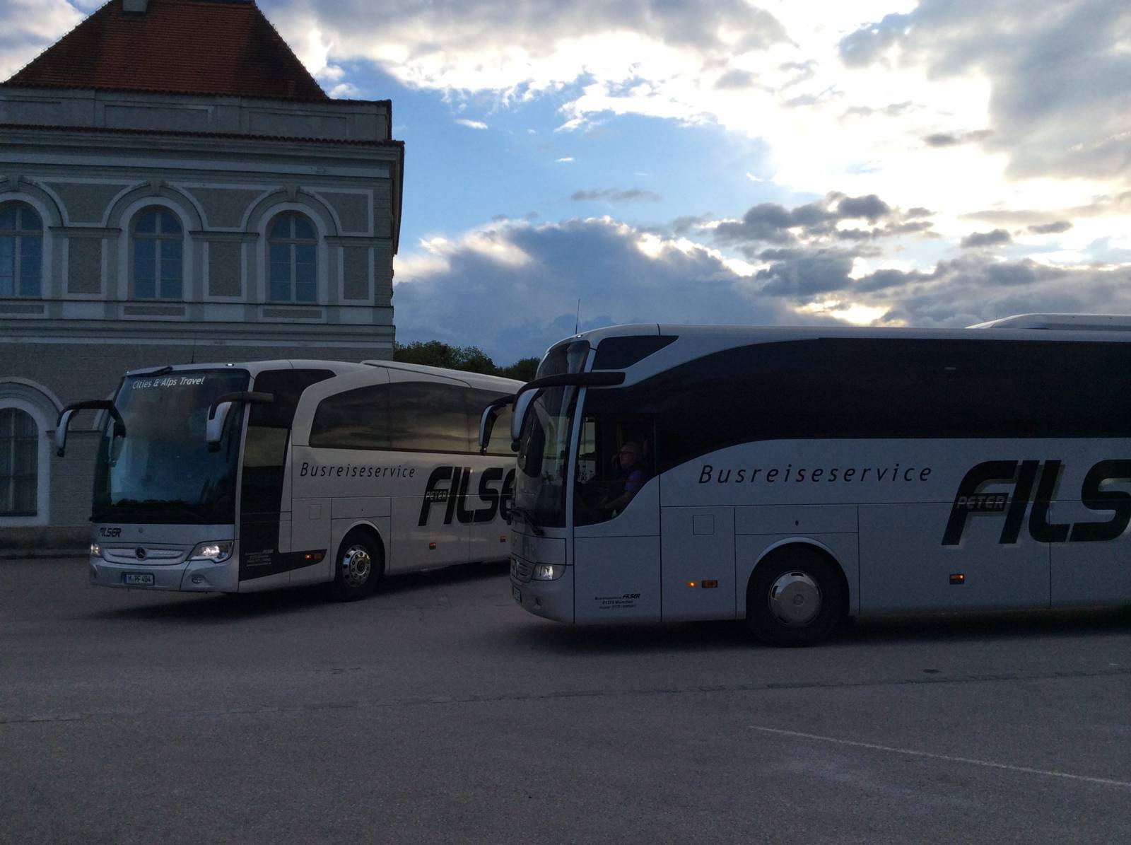 Two Busreisen Filser touring coaches in front of a historic building